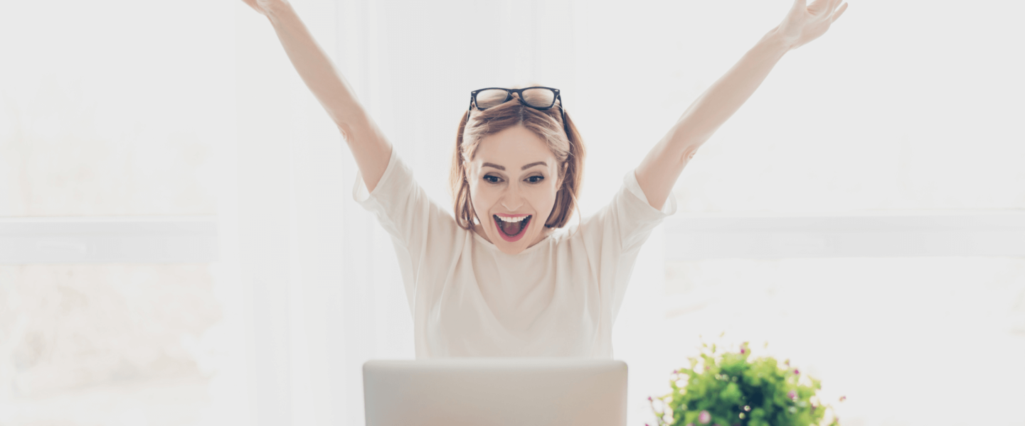 A woman on her laptop, excited about removing student loans from her credit report.