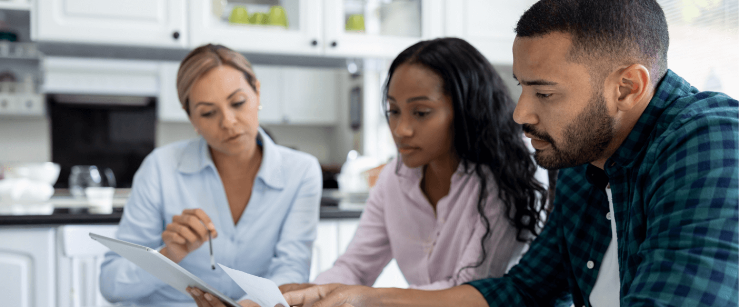 A couple talking to an agent to discuss if they can buy land with bad credit.