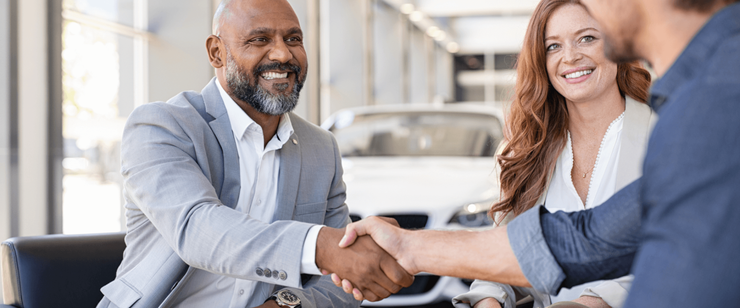 A couple chatting with a car salesman.