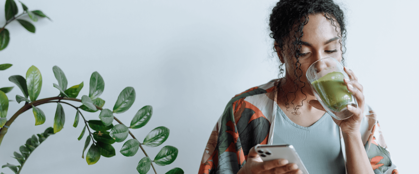 A woman drinking matcha and using her phone to learn about her 665 credit score.