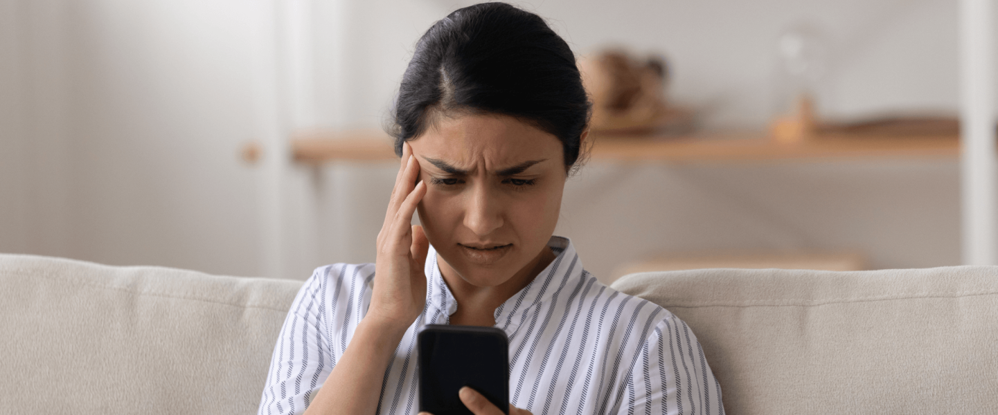 Woman looking frustrated while staring at her phone.