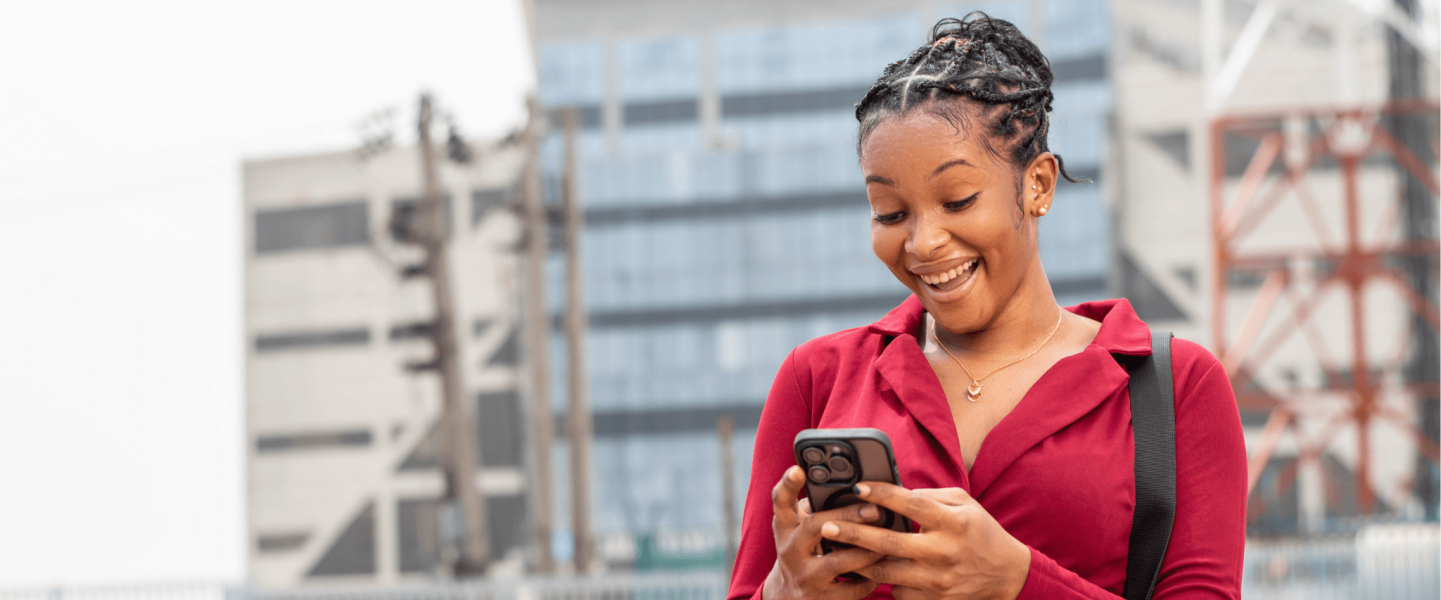 Black woman standing and staring at her phone.