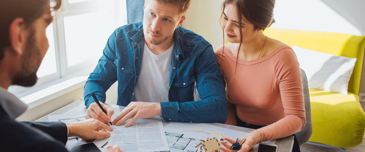 A couple chatting with an agent about buying a home with a 650 credit score.