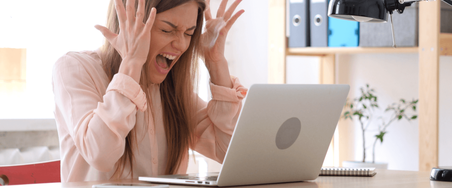 Frustrated woman looking at laptop and realizing her credit score dropped.