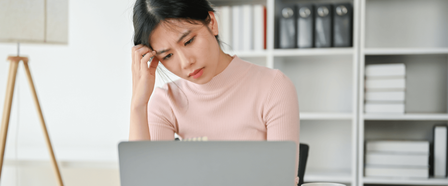 Woman looking at computer and feeling frustrated.